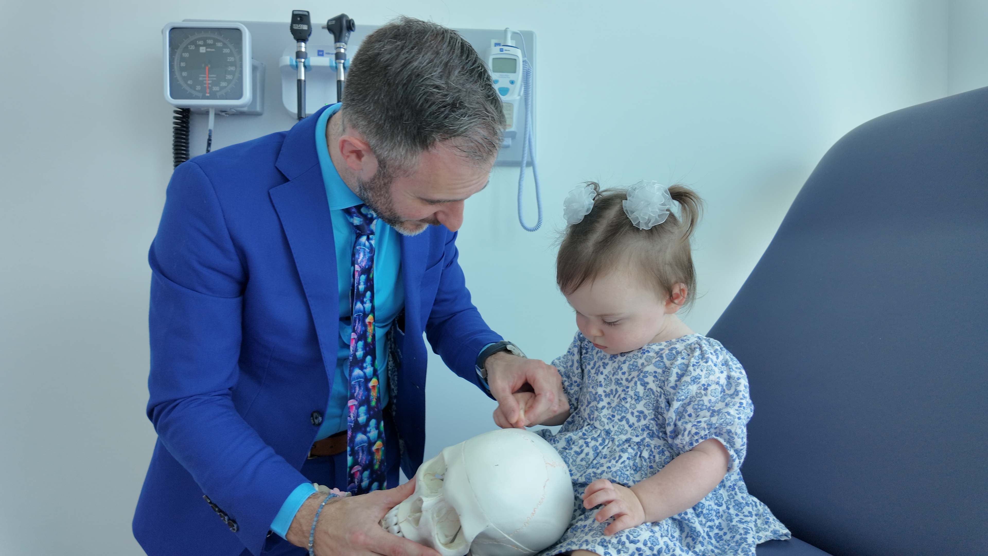 Dr. Stacey in a blue suit showing a skull model to a child.